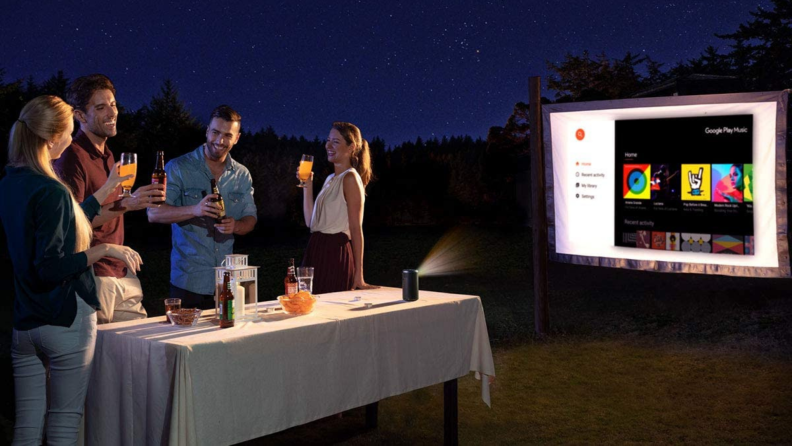 A group of people watch a film outdoor with a mini projector.