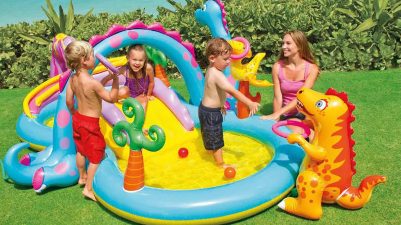 Parents playing outdoors with young children on the Intex Dinoland Play Center.