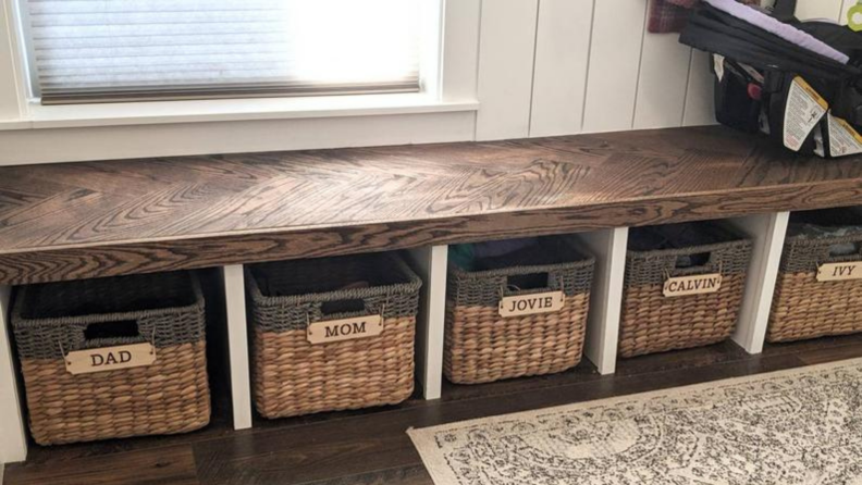 Baskets with name tags sit in cubby holes beneath a bench