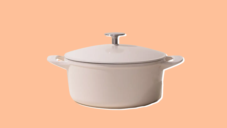 A Made In Round Enameled Cast Iron Dutch Oven in the color Antique White on an orange background.