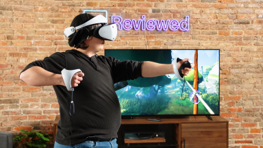 A person wearing a white PSVR 2 headset mimicking pulling back a bow and arrow in front of a TV