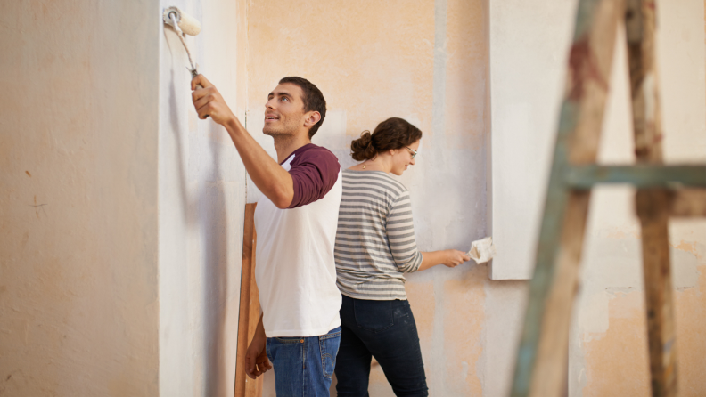 Two people paint walls in a house.
