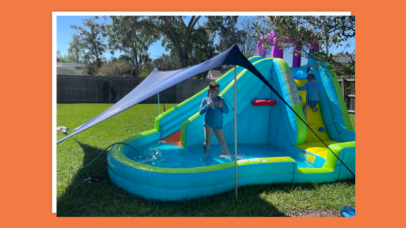 Small child playing in inflatable bouncy castle in backyard.