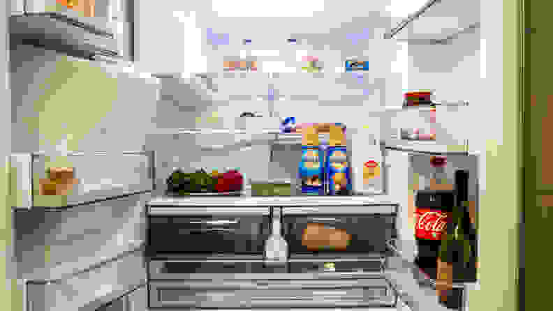 The Samsung RF28R6201SR is opened up, displaying shelves full of food. The left-hand door doesn't have nearly as much stored on it, however, as a large portion is taken up by the ice reservoir.