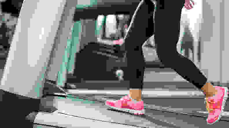 An image of a woman's sneakers while walking uphill on a treadmill.