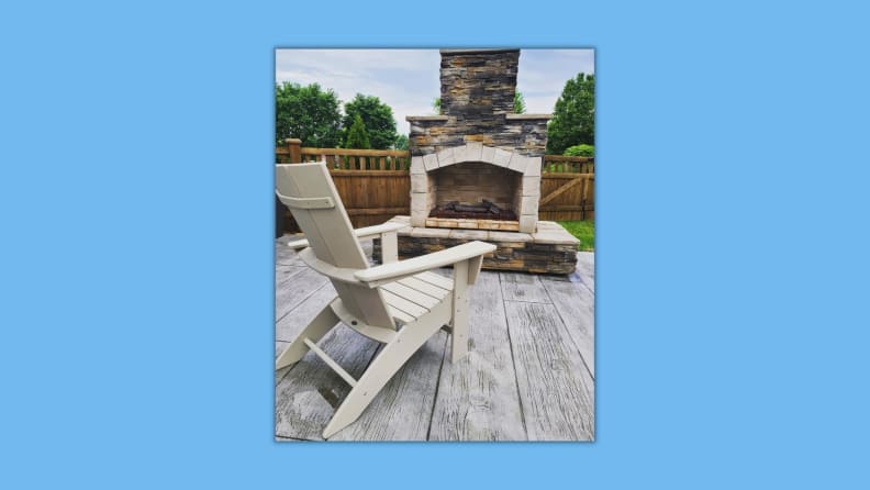 The Polywood Adirondack chair in front of a fireplace.