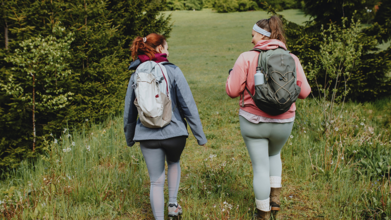 Two people hiking with backpacks in a wooded area