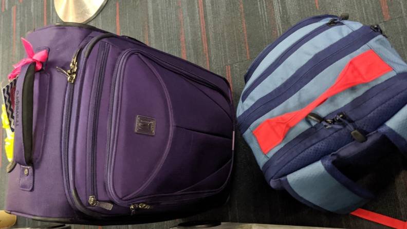 Two carry-on suitcases sit on the floor of an airport.