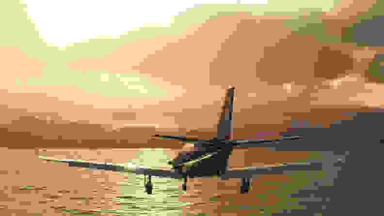 A screenshot of a plane flying above a sea at sunset.