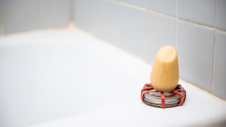 The HiBar Volumize Shampoo Bar sitting on a makeshift holder on the side of a tub.
