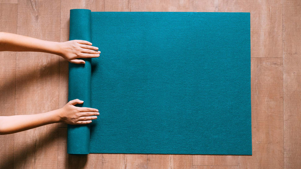 An image of someone rolling up their yoga mat on the floor.