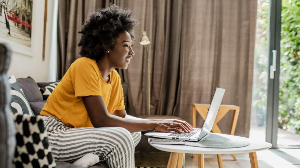 Woman using laptop at coffee table in living room