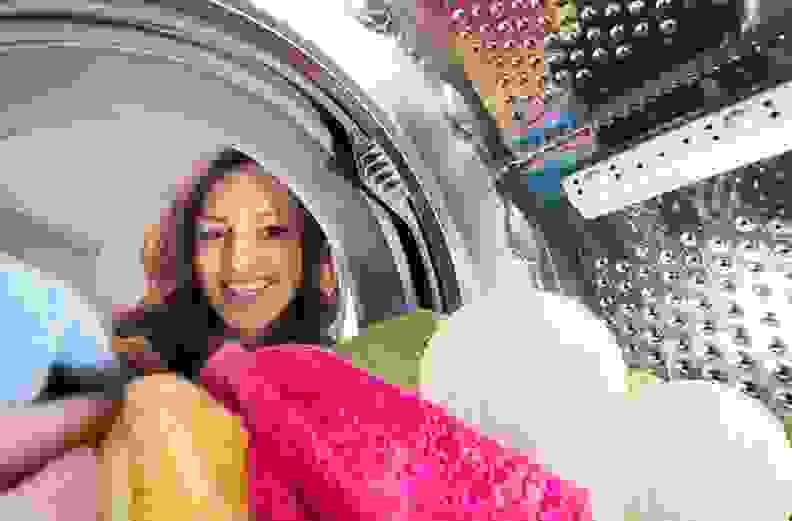 The view from inside the dryer: We see an individual’s face peeking in at the laundry, including colorful towels and a pair of dryer balls.