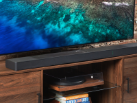 The LG S95TR soundbar sitting right below a flatscreen displaying an ocean.