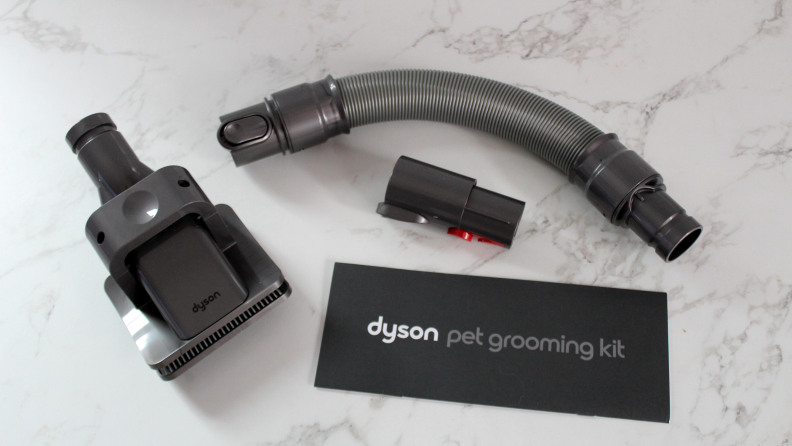 The pieces of the Dyson Pet Grooming Kit, along with the instruction manual