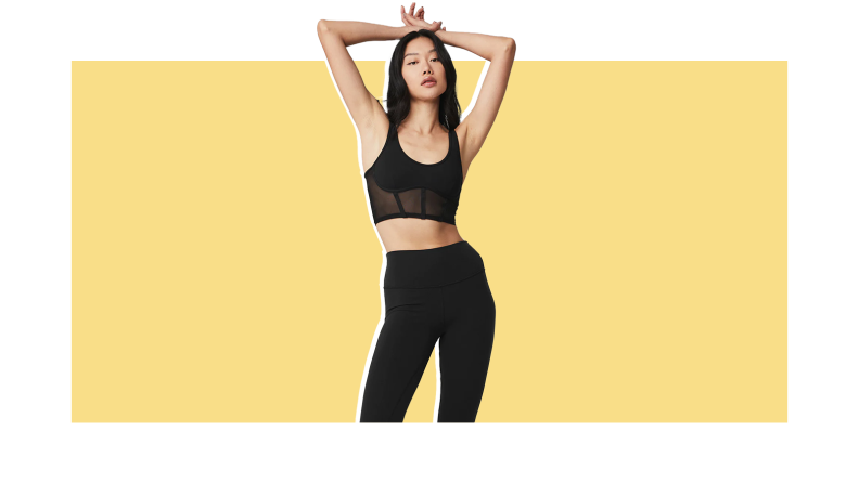 A model wears black athleisure outfit against a yellow background.