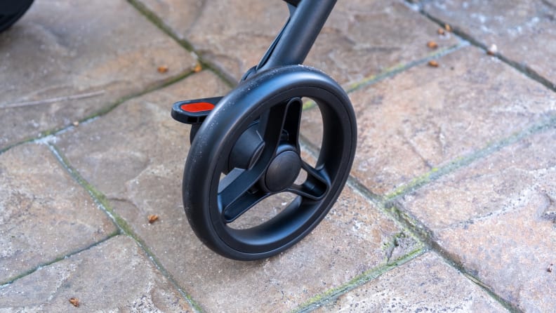 Zoomed-in view of one black wheel of the Mamazing Ultra Air Stroller on a patio.