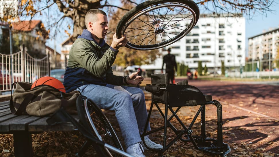 Person outdoors on sports court adjusting wheels for wheelchair.