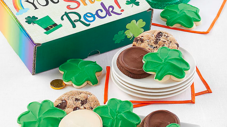 An image of several shamrock shaped Cheryl's cookies in green, alongside chocolate chip cookies and a novelty box.