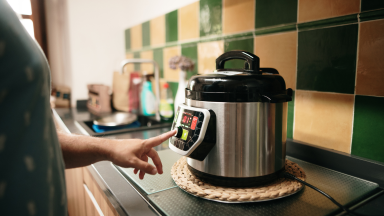 Person pressing button on Instant Pot with finger.