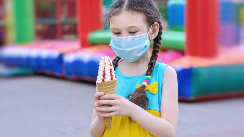 Child wearing face mask holding ice cream cone