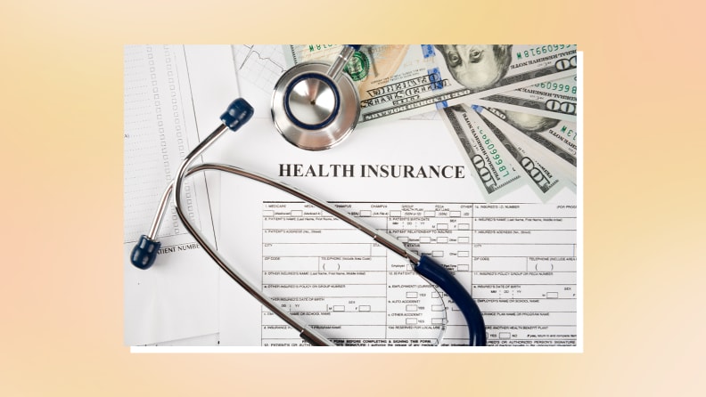 Medical stethoscope next to pile of money on health insurance papers.