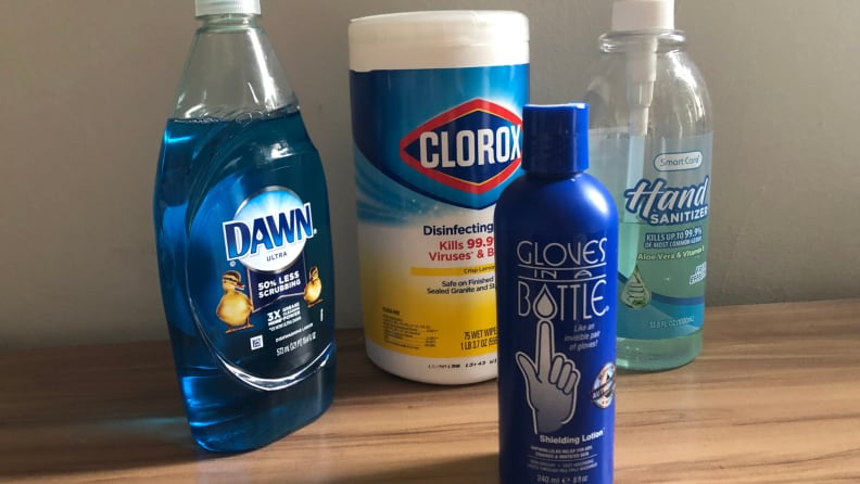 Assorted cleaning products and moisturizer sitting on wooden surface