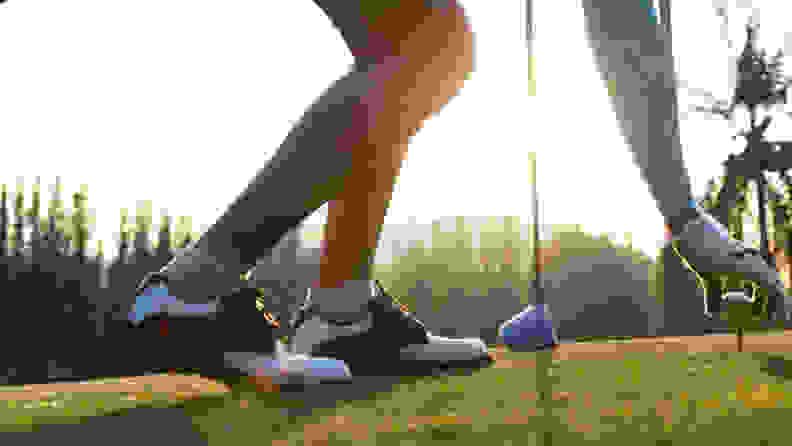 A close-up shot of a woman putting a golf ball on a golf tee