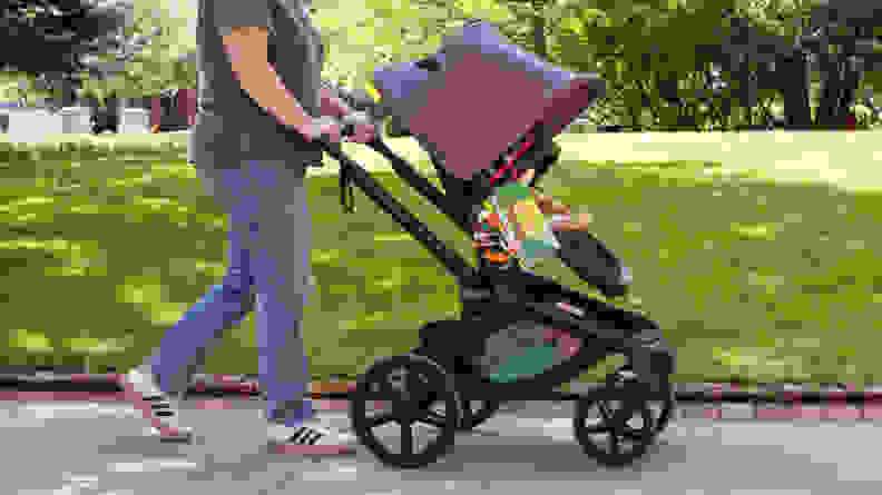 A woman walking in a park with the Bugaboo Fox 5 stroller in the color black.