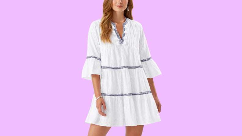 A white cover-up dress with blue embroidery detail.