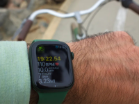 A person holds out their wrist while riding a bike to check a calendar date on their Apple Watch.
