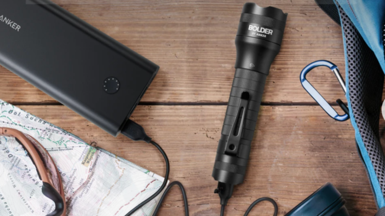 Anker Rechargeable Bolder LC40 LED Flashlight surrounded by charger, map, and glasses.