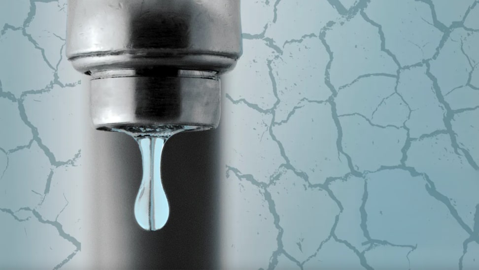 Pipe faucet dripping water surrounded by cracked ground.