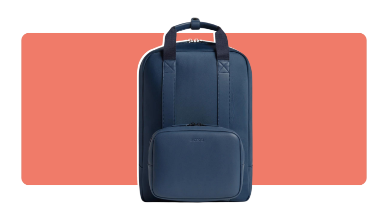 A navy blue Monos Metro Backpack with top handle for carrying located on top.