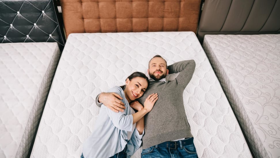 A couple laying down on a mattress in a mattress store.