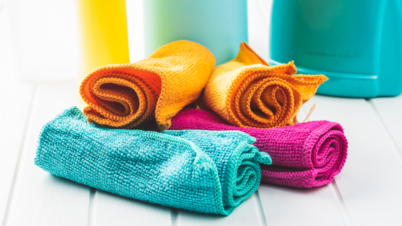 Four teal, orange and magenta microfiber cloths rolled up.