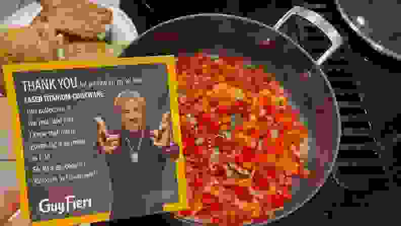 Person holding up a thank you note from Guy Fieiri in front of a skillet filled with chopped up peppers next to a cooked plate of chicken thighs.