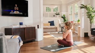 A woman doing yoga in her living room with the Tempo Move.