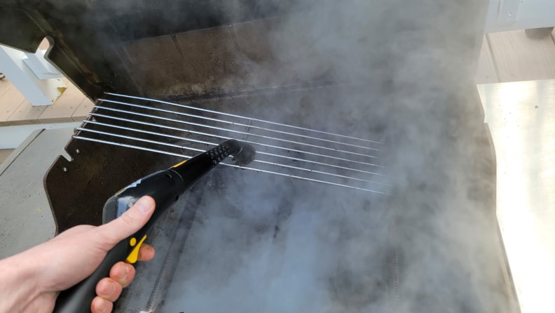 A grill being cleaned with steam from a steamer wand.