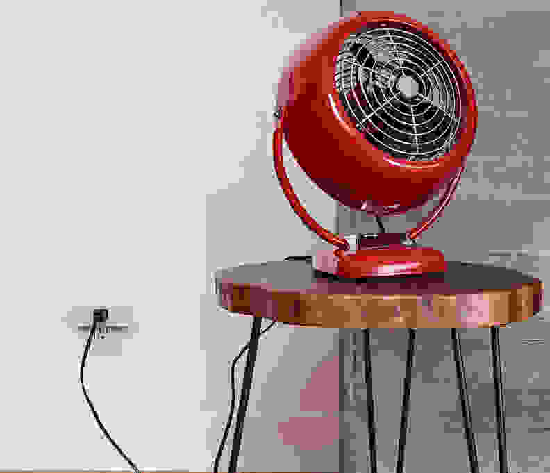 A red fan sits atop a stool.