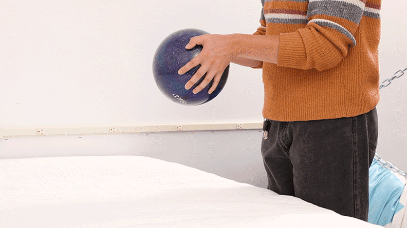 A moving image of a person dropping a bowling ball onto the surface of the Awara Premier mattress.