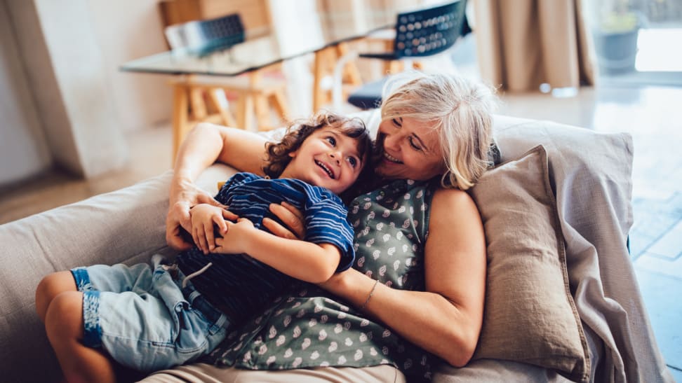 Grandmother and grandson embracing each other on couch at home.