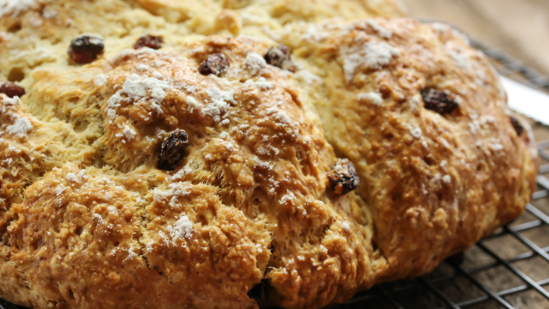 A loaf of Irish soda bread is chilling on a cooling rack.