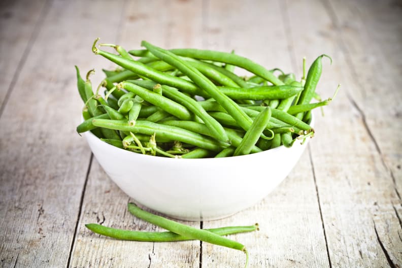 green string beans in a bowl on rustic wooden table