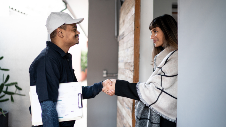 Man and woman standing in threshold of door holding hands.