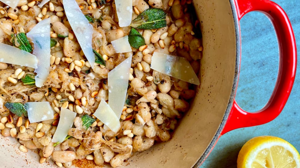 White beans, herbs, and shaved parmesan in a red Dutch oven.