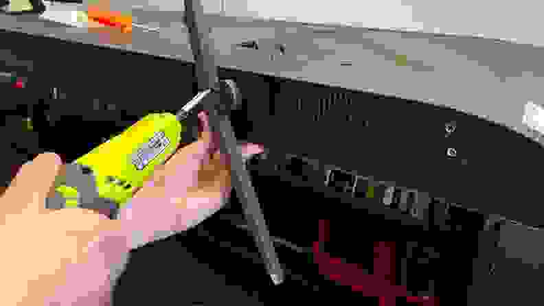 Person using neon green power drill to attach the TV leg stands on to the bottom of the TCL Q6 LED TV.