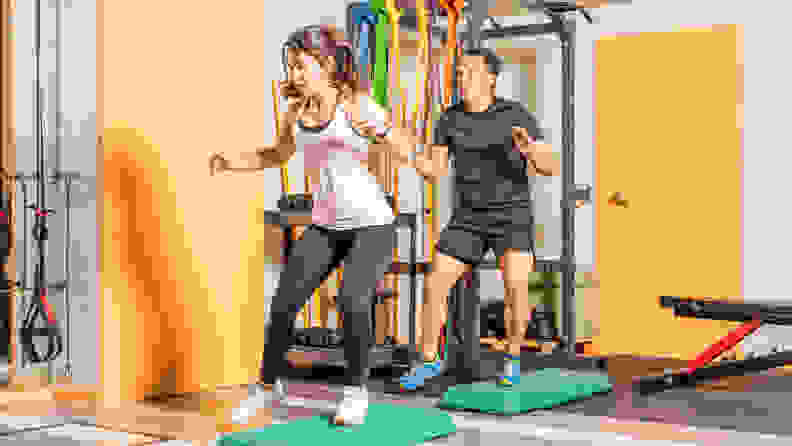 A man and a woman exercising with step-up platforms.
