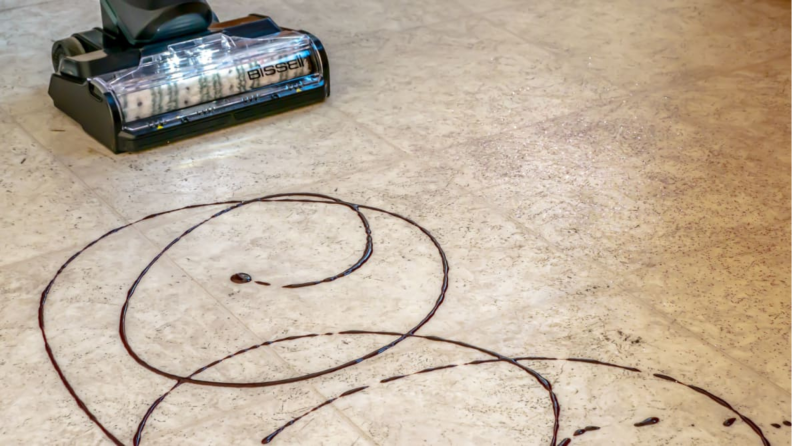 A Bissell CrossWave HydroSteam vacuuming up chocolate syrup.