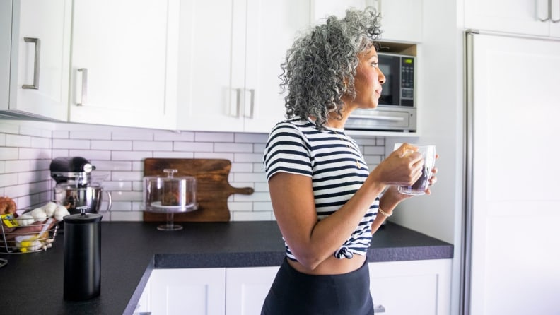 someone stands in the kitchen drinking coffee
